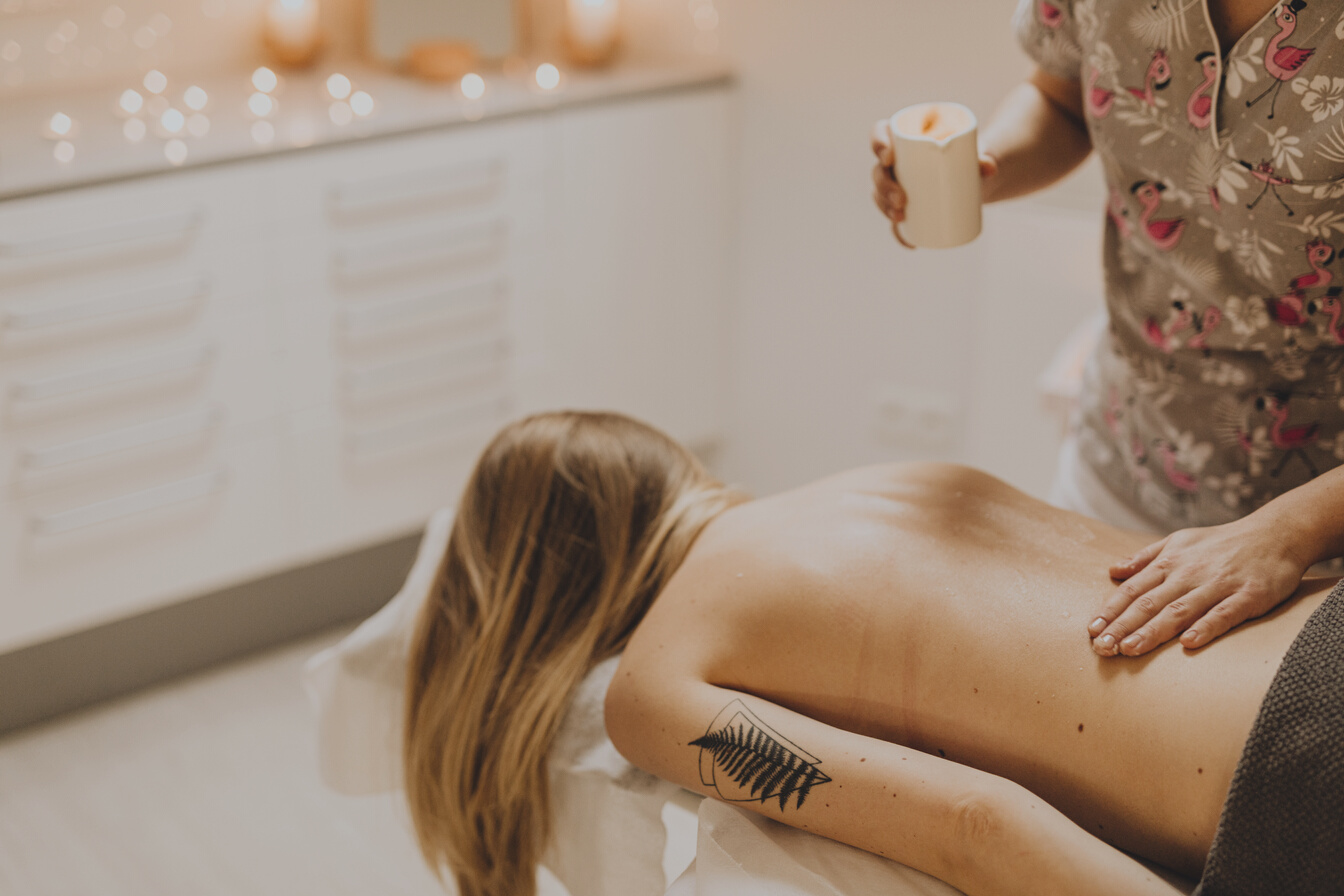 A Masseuse Rubbing Massage Oil on a Woman's Back